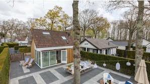 A modern house with a tiled patio, a dining area, and outdoor seating.