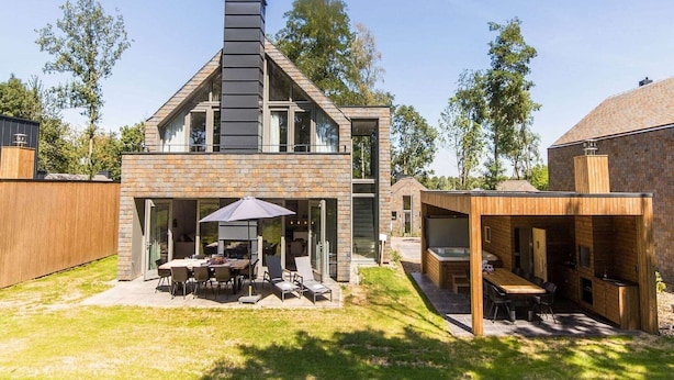 A modern house with a large patio, a dining area, and a separate kitchen area.