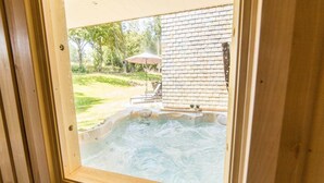 A hot tub with a view of a brick wall and a lawn.