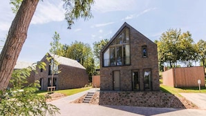 A modern two-story house with a stone facade, large windows, and a visible staircase leading to the entrance.