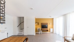 A modern living room with a staircase, a dining area, and a seating area with a sofa and a chair. - Sauna, Garden & Indoor Pool (Maastricht)