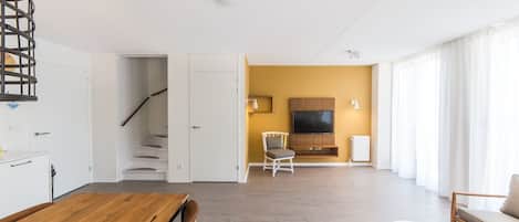 Una sala de estar moderna con una escalera, un comedor y una zona de estar con un sofá y una silla.