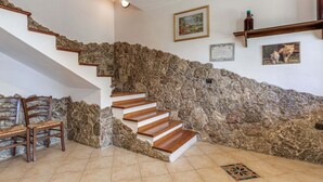 Una escalera con paredes de piedra, escalones de madera y suelo de baldosas.