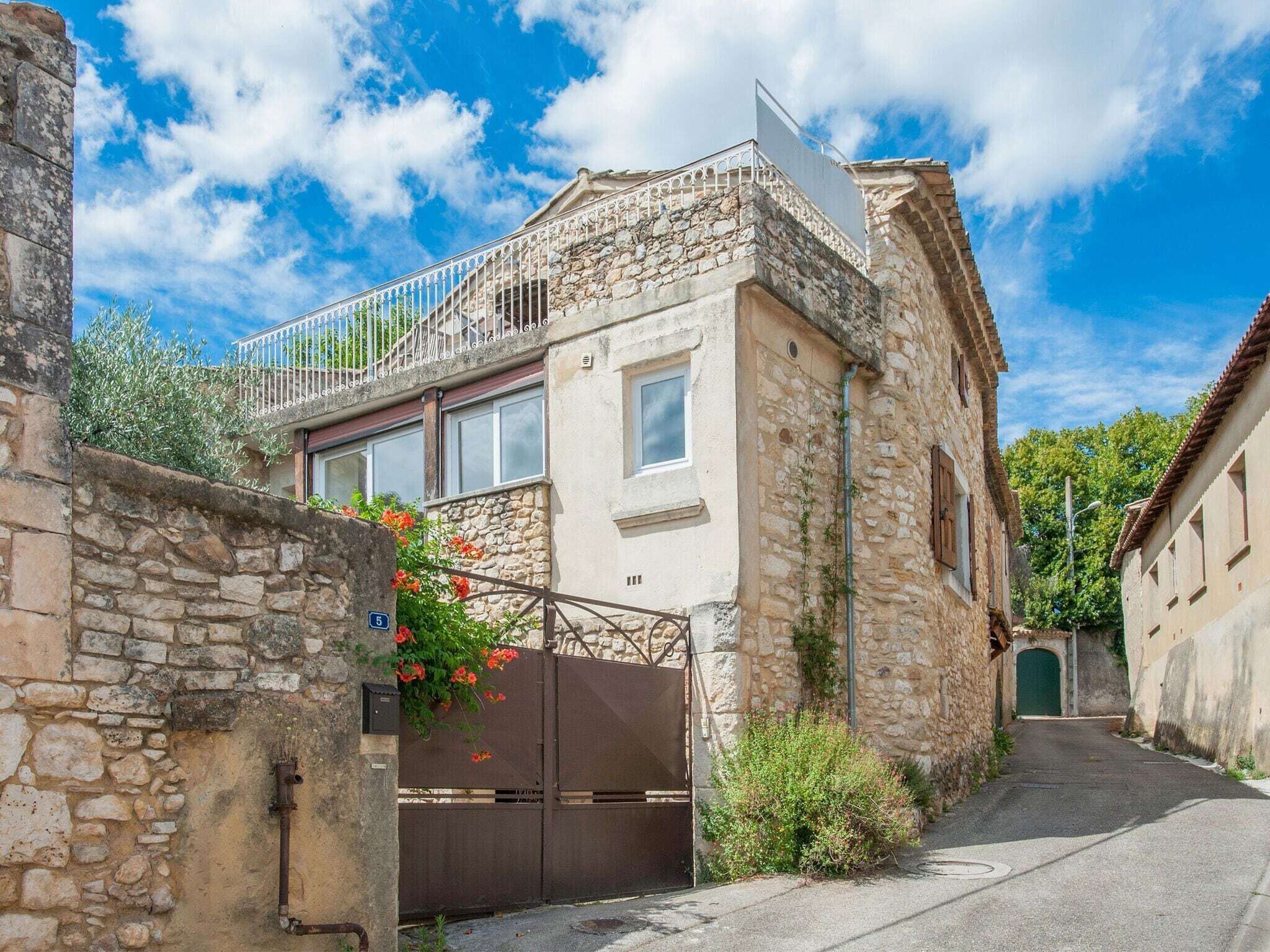 Ein Steinhaus mit Balkon, Tor und einer schmalen Gasse.