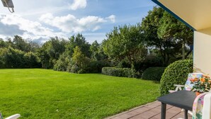 A patio area with a lawn, a table, and two chairs.