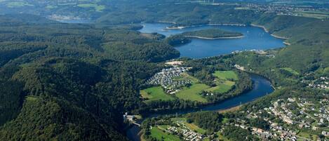 An aerial view of a town with a river, surrounded by dense forests and hills.