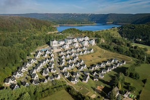 An aerial view of a residential area with multiple houses, a large building, and a lake in the background.