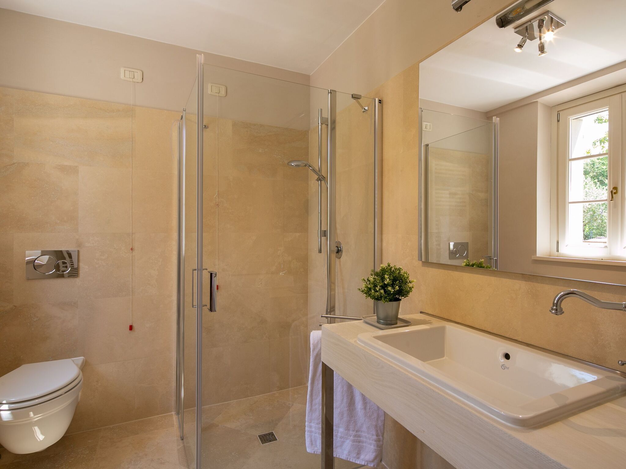 Un baño moderno con cabina de ducha de vidrio, inodoro, lavamanos y espejo.