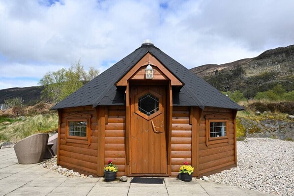 A small wooden cabin with a pitched roof, a central door, and two windows.
