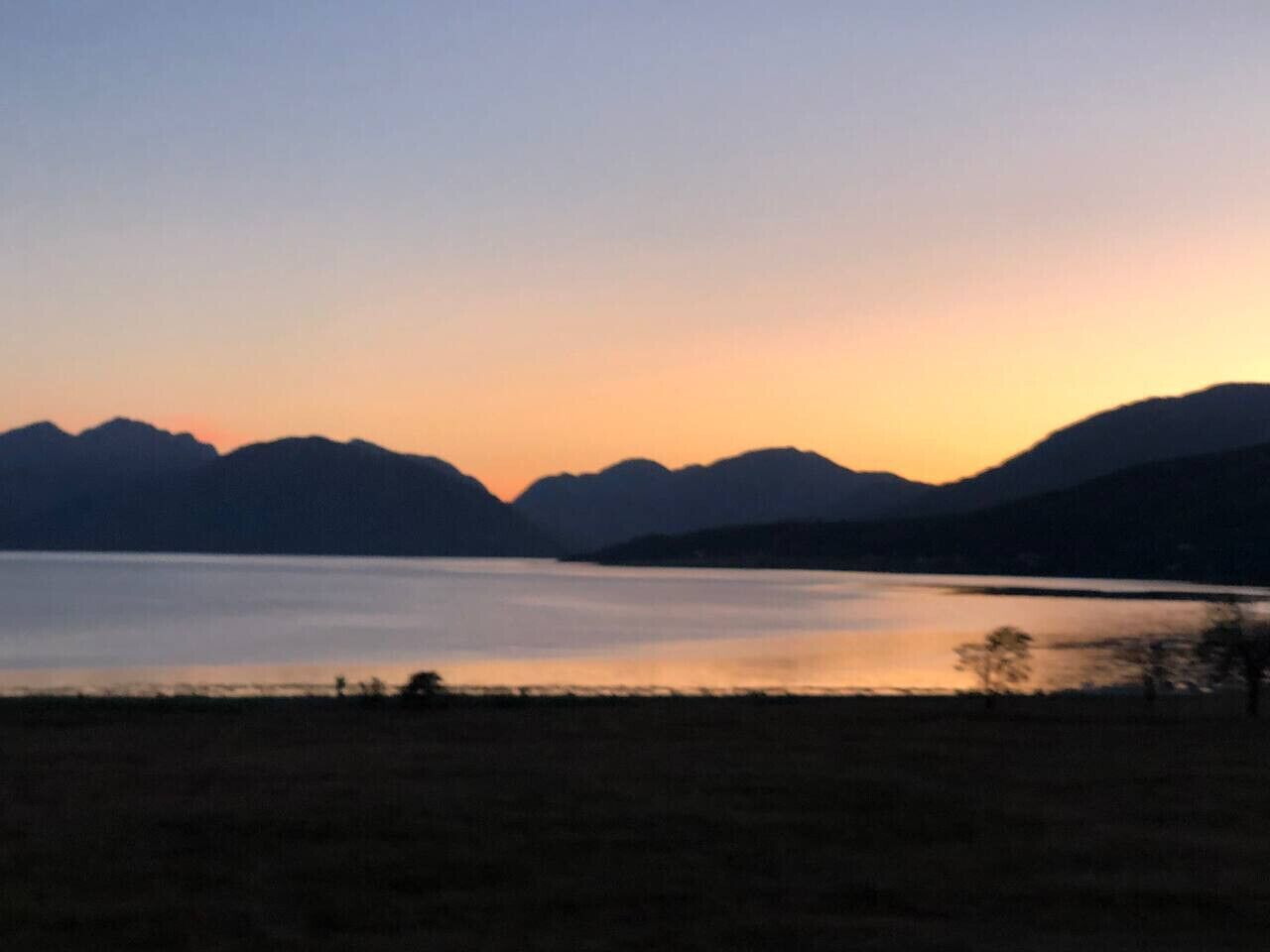 Ein See mit Bergen im Hintergrund im Zwielicht.
