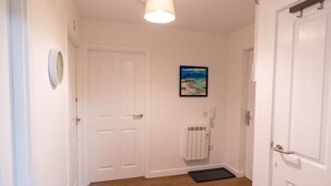 A hallway with white doors, a radiator, a framed painting, and a doormat.