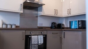 A modern kitchen with white cabinets, a stainless steel range hood, a coffee maker, a toaster, and a microwave.