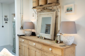 Une commode en bois avec un miroir, deux lampes et divers objets décoratifs.