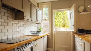 A kitchen with white cabinets, a wooden countertop, a built-in oven, and a window with a view of greenery.