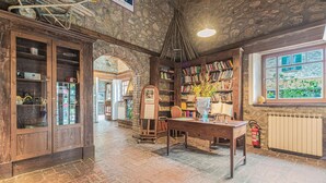 A rustic library with wooden bookshelves, a wooden table with a vase, and a stone ceiling. - Holiday Home in Ficulle with Pool Access (Ficulle)
