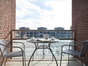Een balkon met twee stoelen, een tafel en een waterkoker.