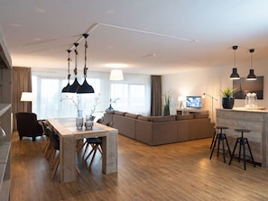 Un soggiorno moderno con un tavolo da pranzo in legno, un divano e una TV.