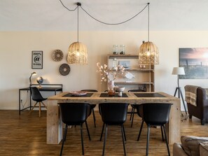 Een eethoek met een houten tafel, zwarte stoelen en hanglampen.