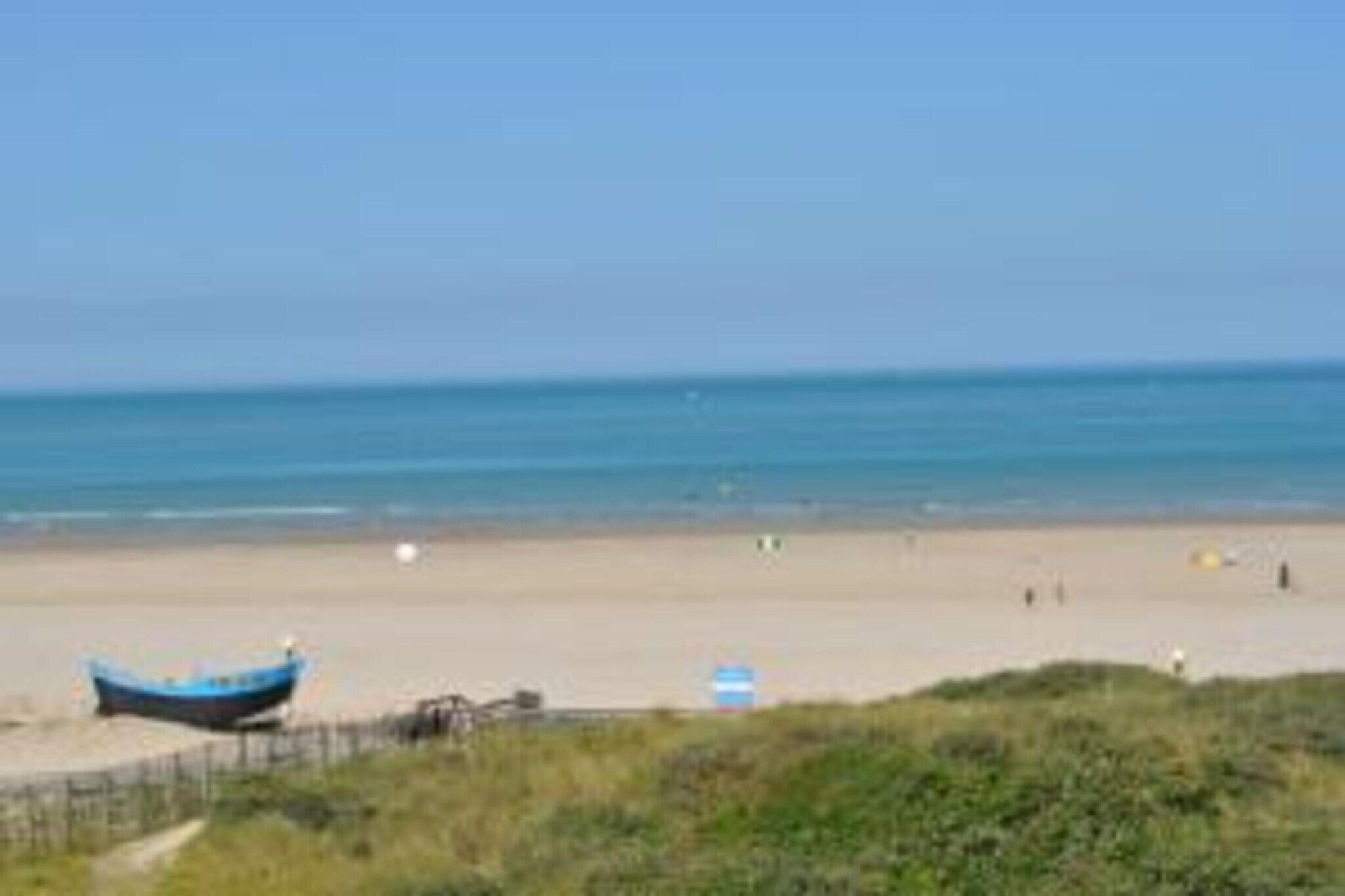 A beach with a boat, a clear sky, and a sandy shore.