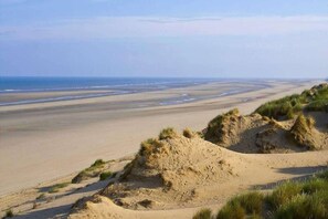 A coastal landscape with sand dunes and a beach.