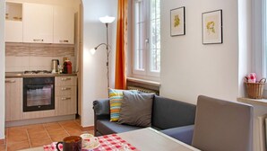 Een moderne keuken met een oven, een eethoek met een tafel en stoelen, en een bank.