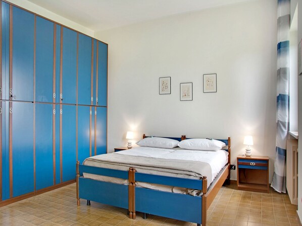 Un dormitorio con cama, dos mesitas de noche, un armario y tres cuadros en la pared.