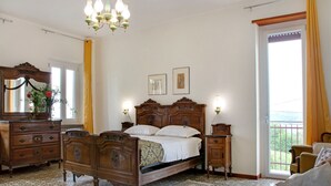 Een slaapkamer met een houten bed, een kapstok, een spiegel en een kroonluchter.