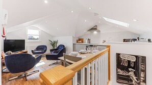A modern loft apartment with a dining area, seating, kitchen, and a view of the city. - Central Cosy Harrogate Apartment (North Yorkshire)