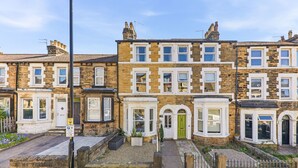 A row of terraced houses with a front garden, a green door, and a parking sign. - Central Cosy Harrogate Apartment (North Yorkshire)