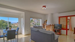 A spacious living area with a sofa, a dining table with chairs, a TV, and a view of the sea. - Vacation home Mimosa by Interhome (Calpe/Calp)