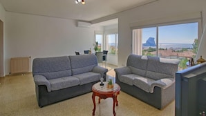 A living room with two grey sofas, a small wooden table, and a TV. There is a large window with a view of the sea and mountains. - Vacation home Mimosa by Interhome (Calpe/Calp)