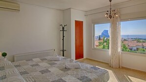 A bedroom with a large bed, a view of a mountain and cityscape through a window, a coat rack, and a radiator. - Vacation home Mimosa by Interhome (Calpe/Calp)