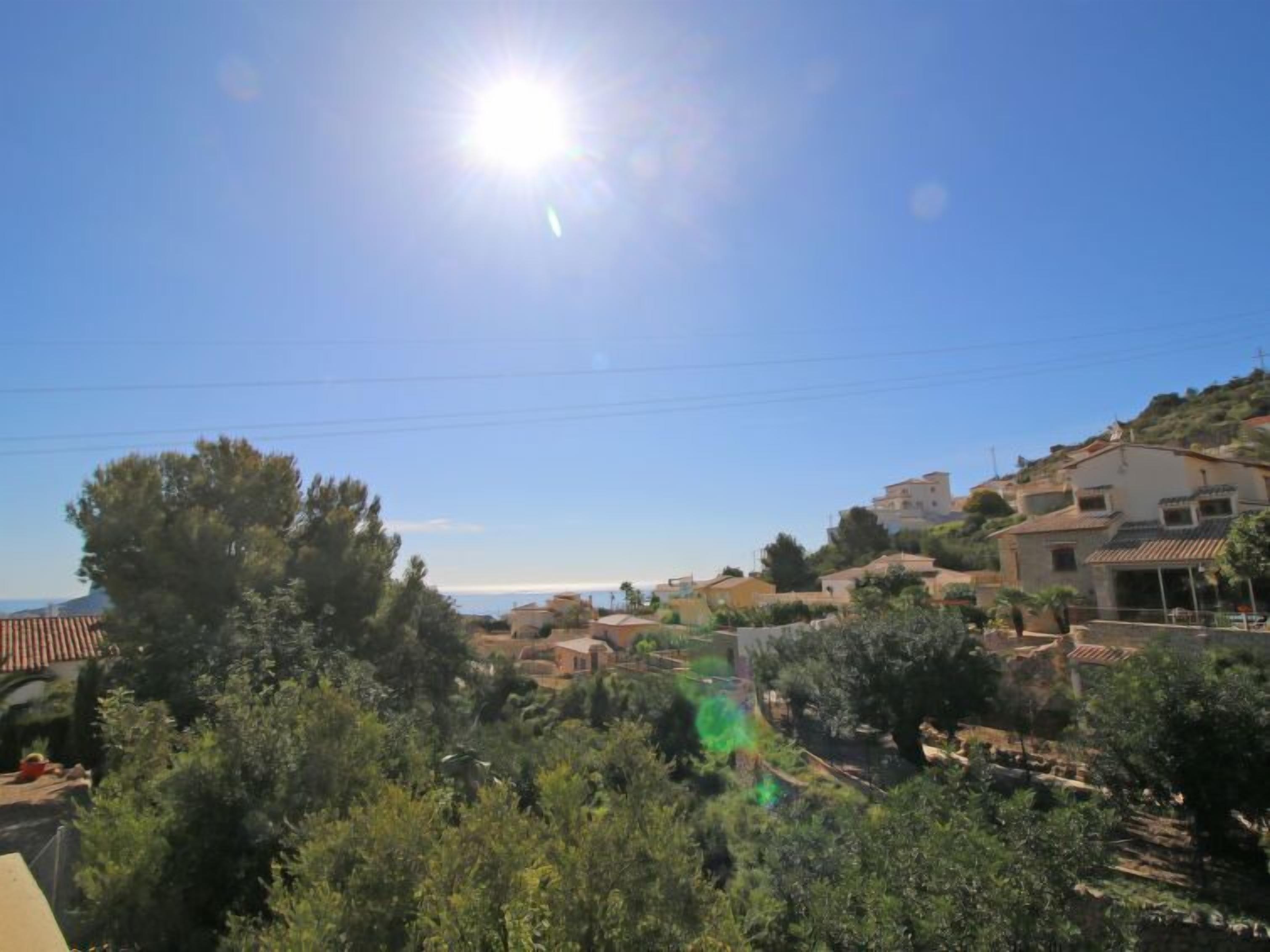 A residential area with houses on a hillside, surrounded by greenery.