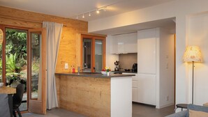 A modern kitchen with a central island, wooden accents, and a view of greenery outside. - Sernisa Rez by Interhome (Verbier)