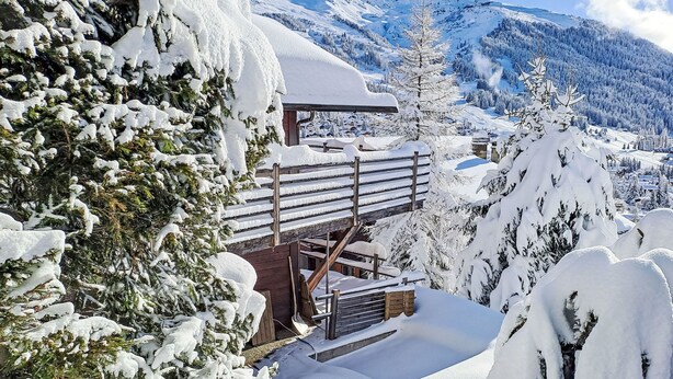 A wooden chalet with a snow-covered roof and a wooden staircase leading up to it, surrounded by snow-laden trees and mountains in the background. - Sernisa Rez by Interhome (Verbier)