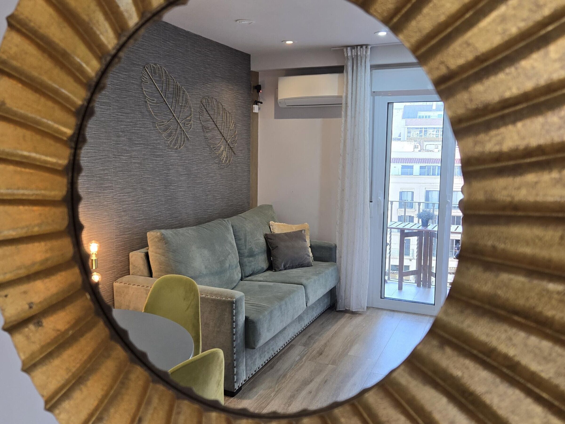 A modern living room with a grey sofa, a small green chair, and a decorative wall piece.