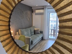 A modern living room with a grey sofa, a small green chair, and a decorative wall piece.