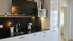 Una cocina moderna con televisor de pantalla plana, microondas y refrigerador.