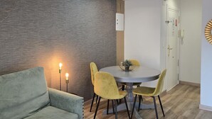 Un comedor con una mesa redonda, cuatro sillas y una lámpara en la pared.