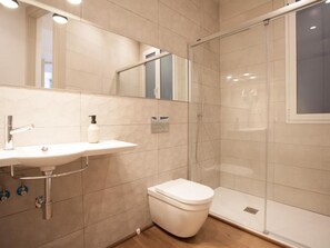 Un baño moderno con lavamanos, inodoro y cabina de ducha de vidrio.