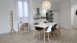 A modern kitchen with white cabinets, a stainless steel refrigerator, and a hanging light fixture.