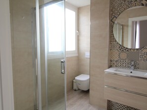 A modern bathroom with a glass shower enclosure, a toilet, and a sink with a mirror. - 3-bed, 2-bath apartment, equipped kitchen, central Malaga (Málaga)