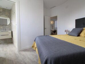 Ein Schlafzimmer mit einem Bett, einem Nachttisch, einer Lampe und einem Spiegel.