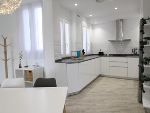 Une cuisine moderne avec des armoires blanches, une hotte de cuisinière en acier inoxydable et un plan de travail noir.