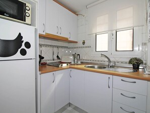 A kitchen with white cabinets, a wooden countertop, a sink, a microwave, and a stove. - Amazing apartment with large terrace 3 min from the beach - Malagueta (Málaga)
