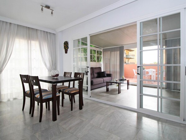 A spacious living area with a dining table and chairs, a sofa, and a sliding glass door leading to an outdoor patio. - Amazing apartment with large terrace 3 min from the beach - Malagueta (Málaga)