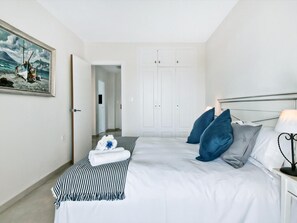 Ein ordentlich eingerichtetes Schlafzimmer mit Bett, Kissen, einer Nachttischlampe und einem Bild an der Wand.