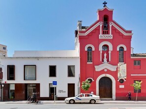 A red church with a bell tower and a white building with a blue sign. - Stunning duplex with terrace in the heart of Malaga (Málaga)
