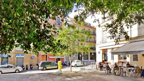 Straßenansicht mit einem Café, parkenden Autos und Gebäuden.