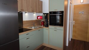 Una cocina compacta con refrigerador, lavamanos y cafetera.